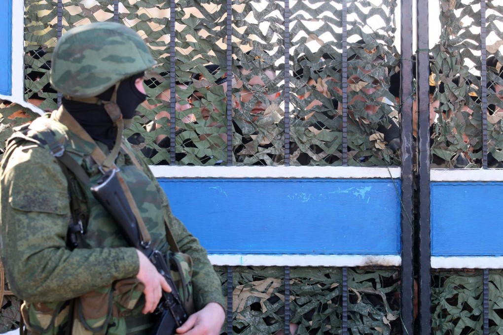 An armed man in military uniform, believed to be Russian, blocks the entrance of the Ukrainian naval headquarters in the Crimean city of Sevastopol yesterday. Similar forces have sealed off several military posts in the region. Photo: EPA