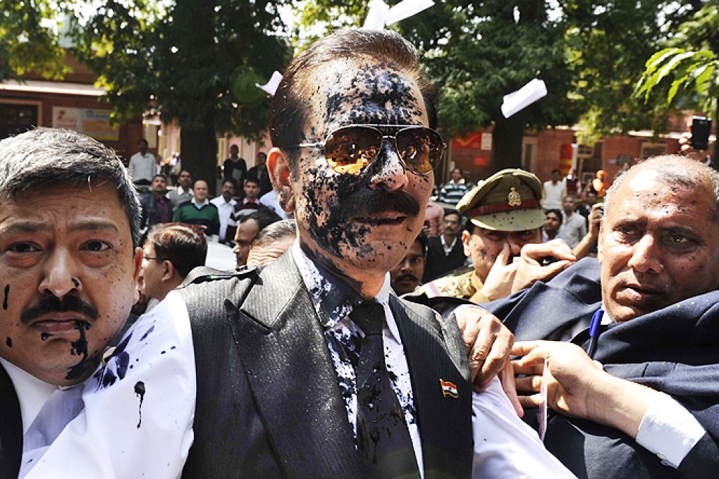 Chairman of Sahara India Pariwar Subrata Roy, his face smeared with ink thrown by a lawyer, walks into the Supreme Court in New Delhi, India, on Tuesday. Photo: AP