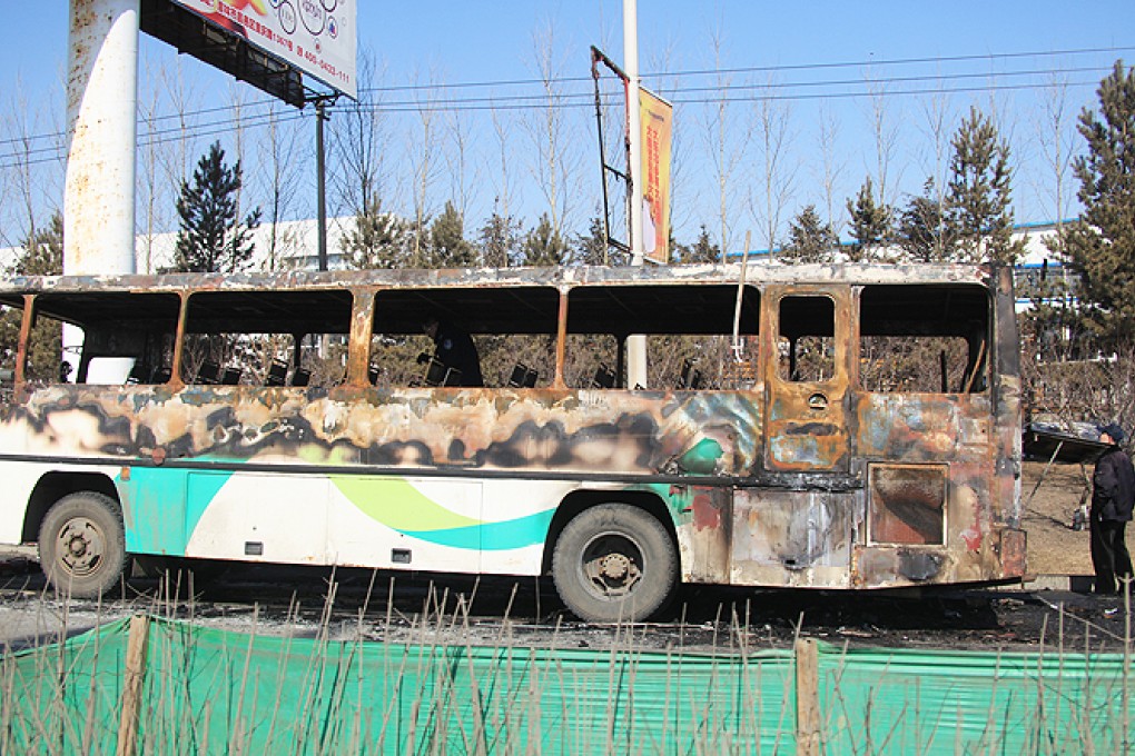 A man inspects the remains of a company shuttle bus after it caught fire, in Jilin, northeast China's Jilin province. Photo: Xinhua