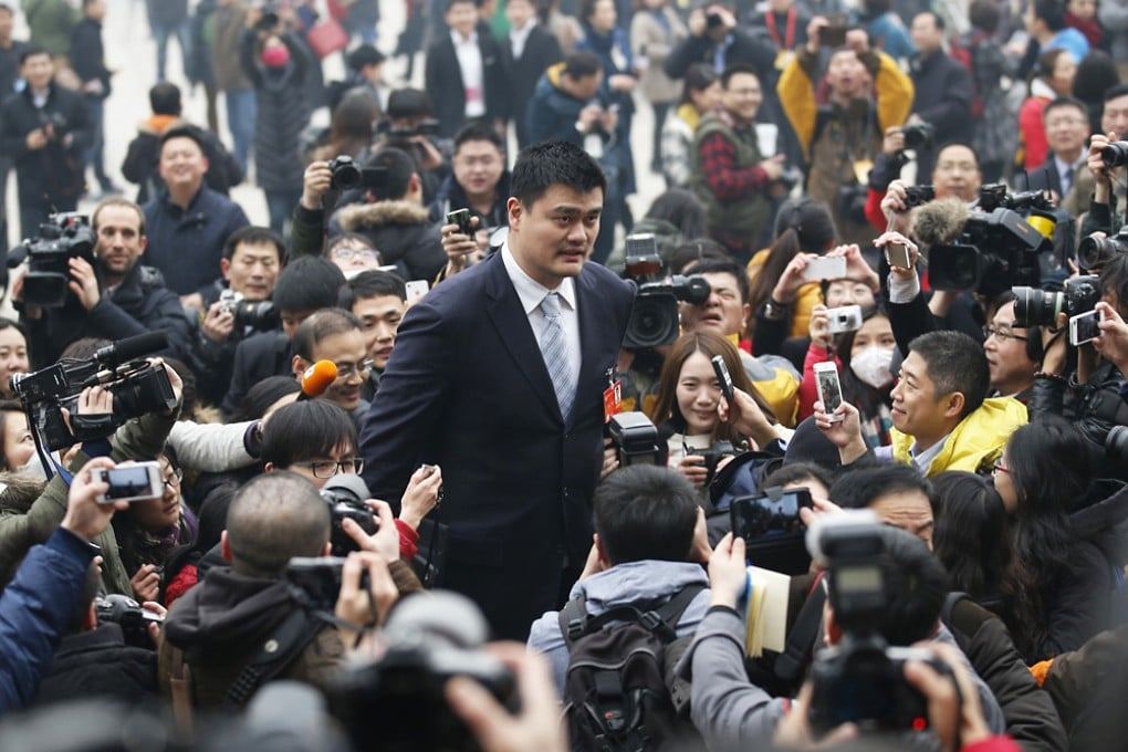 Yao Ming (centre) towers over reporters as he heads to the CPPCC meetings in Beijing. Photo: Reuters