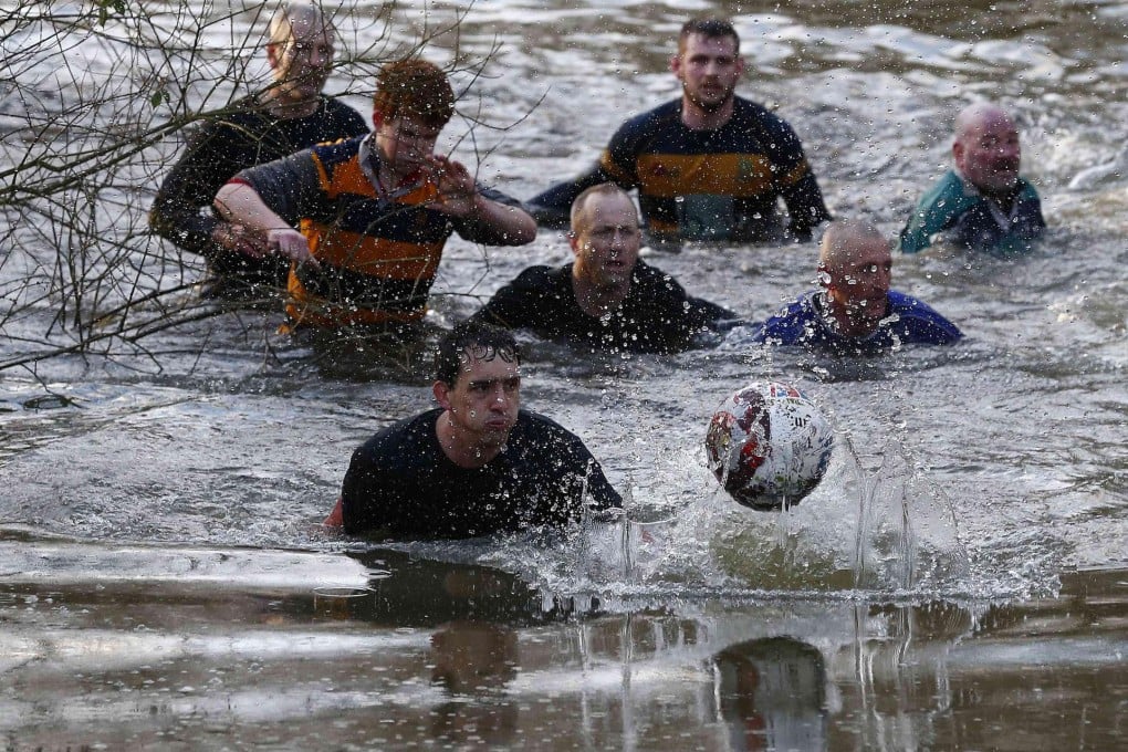 Players chase the ball through a pond. Photo: Reuters