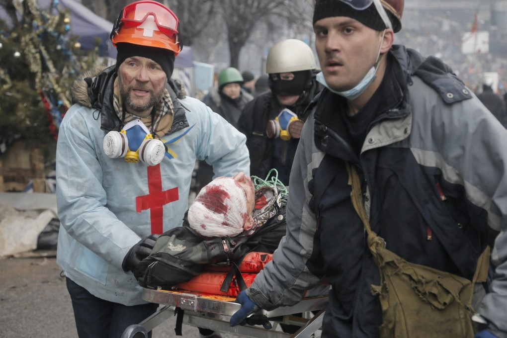 Activists evacuate a wounded protester during clashes in Kiev. There are now questions about who was behind sniping attacks in the city. Photo: AP