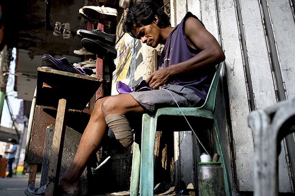 Shoe repair worker Alberto Tiong earns US$6 a day from his Manila street stall. Photo: AFP