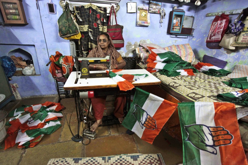 An Indian woman stitches Congress party flags ahead of parliamentary elections in India. Photo: AP