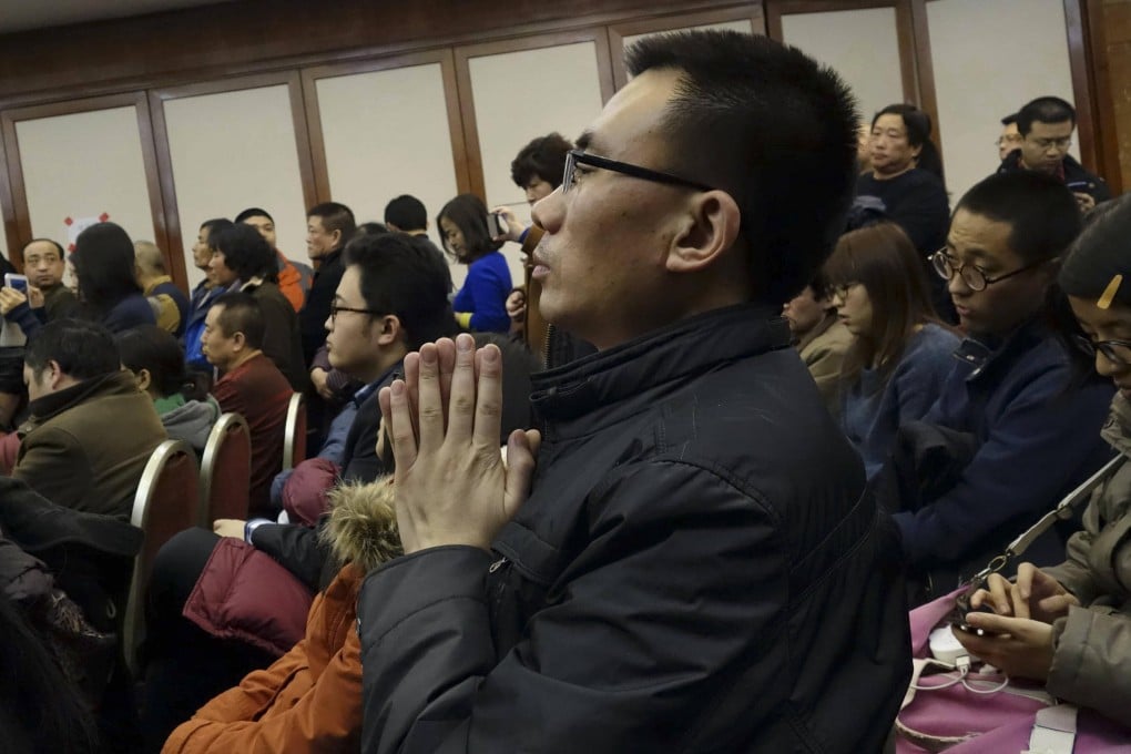 A man prays at the Metropark Lido Hotel in Beijing, which has been converted into an information and assistance centre for passengers' relatives. Photo: AP