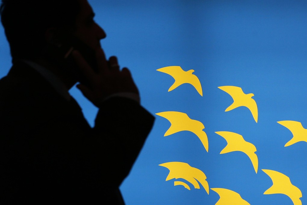 A visitor talks on a mobile phone as he passes an illuminated advertising panel at the Mobile World Congress in Barcelona. Photo: Reuters