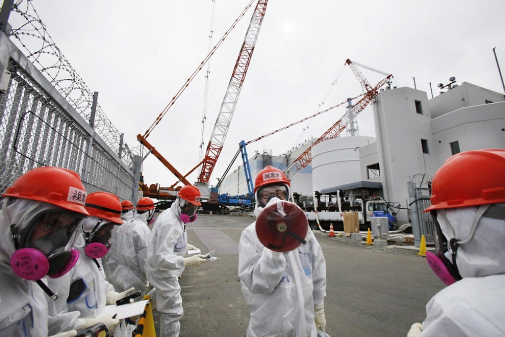 A staff member of the Tokyo Electric Power Co. (TEPCO) speaks in front of the No. 1 reactor at the Fukushima Dai-ichi nuclear power plant during a press tour in Okuma, Fukushima. Photo: AP