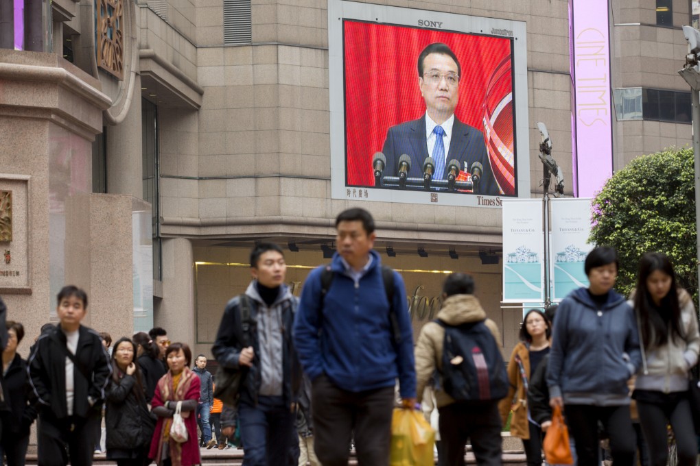 Hong Kong people walk past a monitor at Times Square, Causeway Bay, showing Premier Li Keqiang's speech at the NPC last week. Photo: Bloomberg