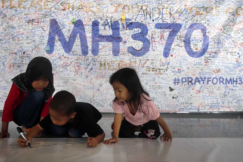 Young children write messages on banner filled with signatures and well wishes for all involved with the missing jetliner at Kuala Lumpur International Airport. Photo: AP