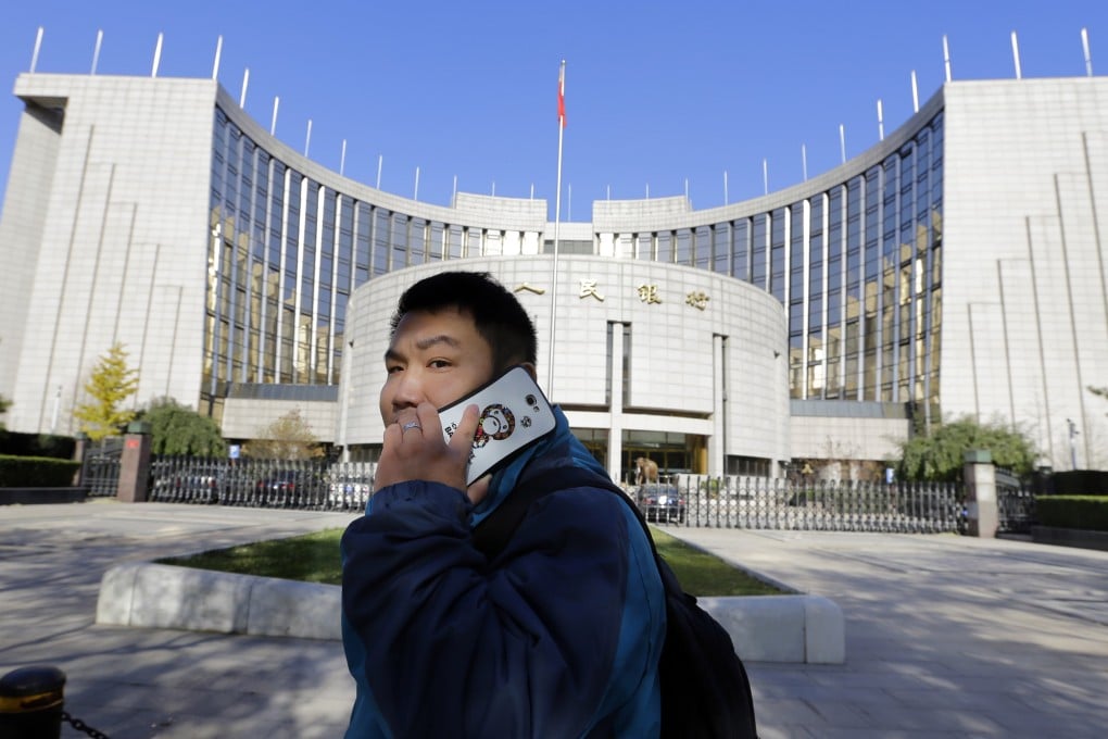A man uses his mobile phone while walking past the headquarters of the People's Bank of China (PBOC), the central bank, in Beijing. Photo: Reuters