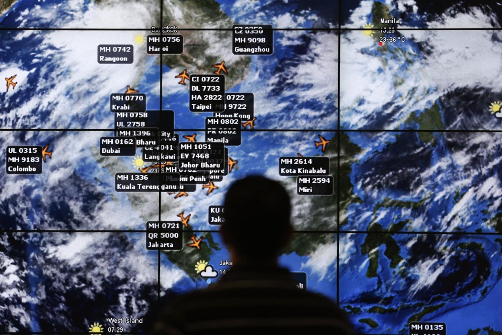 A man watches a large screen showing different flights in the region where experts first thought MH370 had disappeared. Photo: Reuters