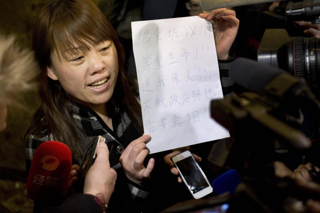 A woman holds up a piece of paper saying, "Hunger strike protest. Respect life. Return my relative", after a briefing by an airline representative in Beijing. Photo: AP