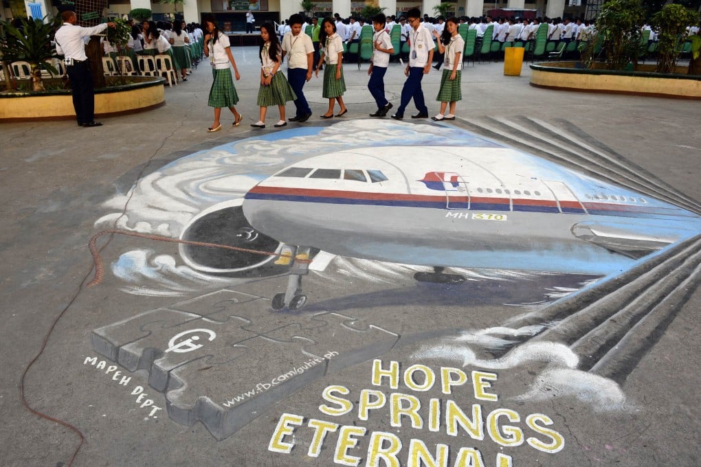 Students walk past a giant mural featuring missing Malaysia Airlines flight MH370 displayed on the grounds of their school in Manila. Three million people have joined an effort led by a satellite operator to locate the missing Malaysia Airlines plane. Photo: AFP