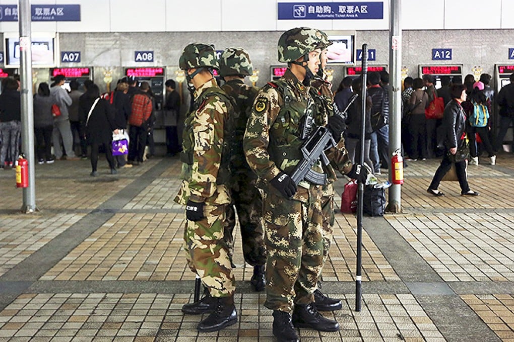 Armed paramilitary policemen stand guard next to ticket booths after at Kunming railway station. Photo: Reuters