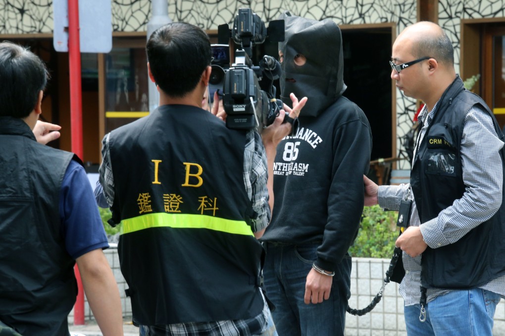 One of the two suspects is escorted through Hong Kong yesterday to assist police with a reconstruction of the crime. Photo: David Wong