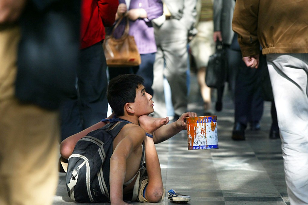 A disabled beggar begs for alms from passersby along a street in downtown Shanghai. Photo: AFP