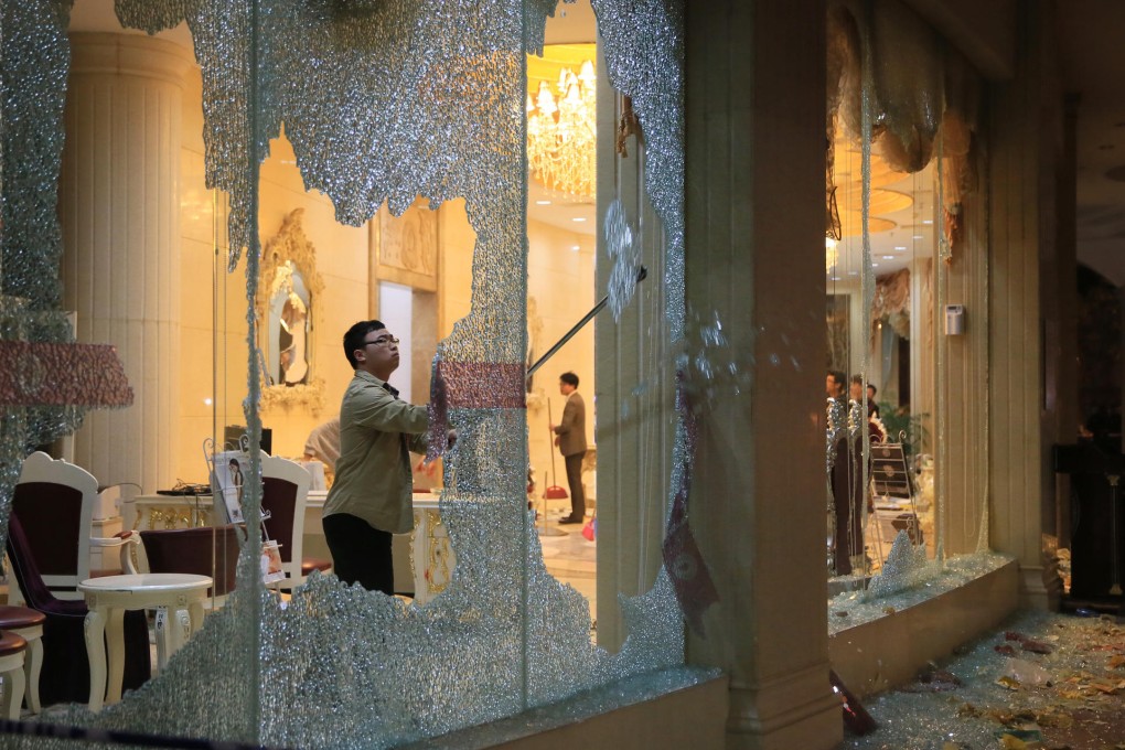 A worker cleans up glass from a window smashed by relatives of a pregnant woman who were angry about the death of her fetus at Guangzhou Elizabeth Women's Hospital in December last year. Photo: Imaginechina