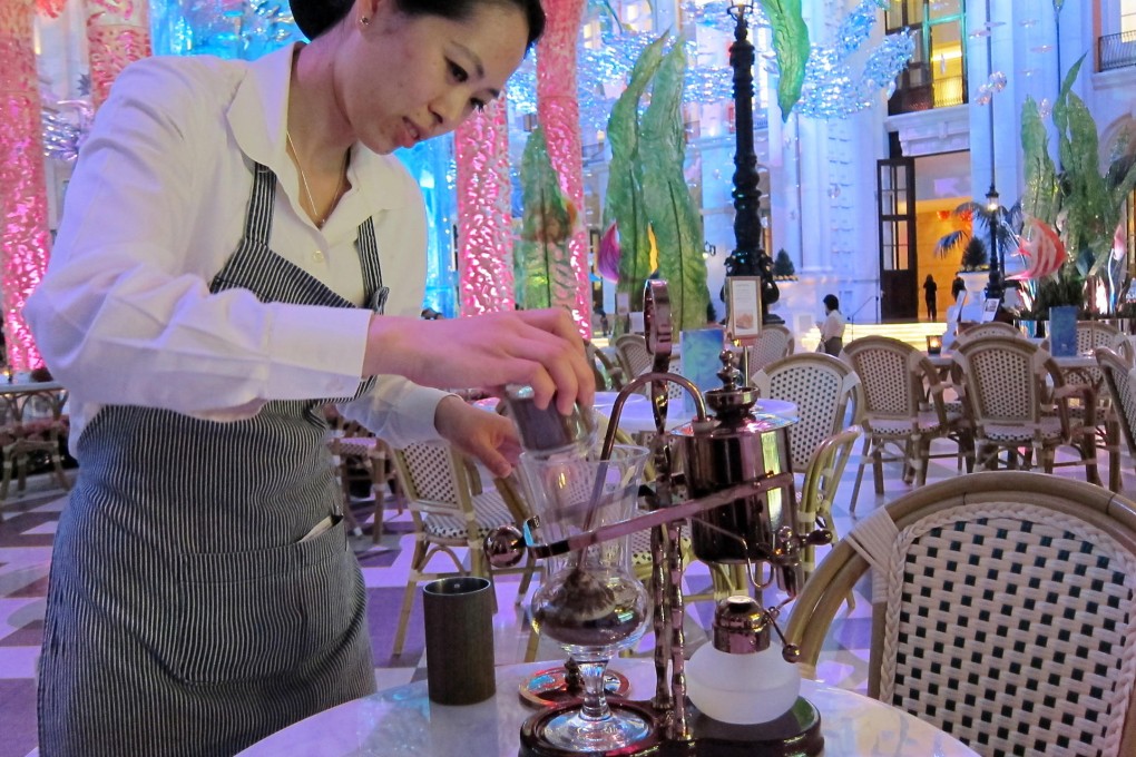 An MGM Macau staff member grinds "elephant dung" coffee beans by hand before serving up the rarefied brew. Photo: Lana Lam