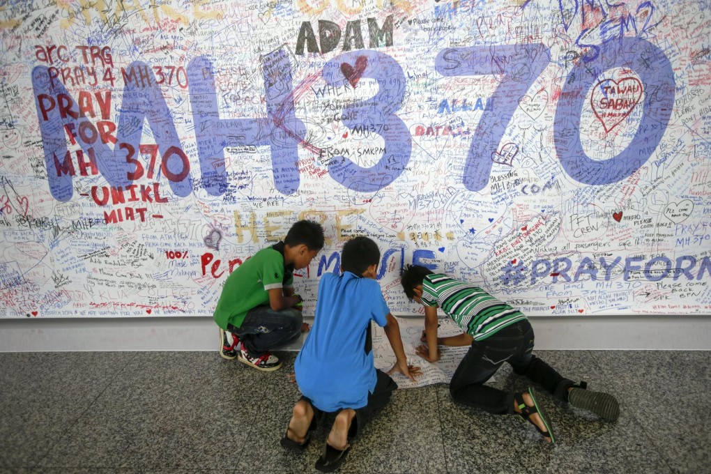 Children write a message at the Wall of Hope for the missing jet.