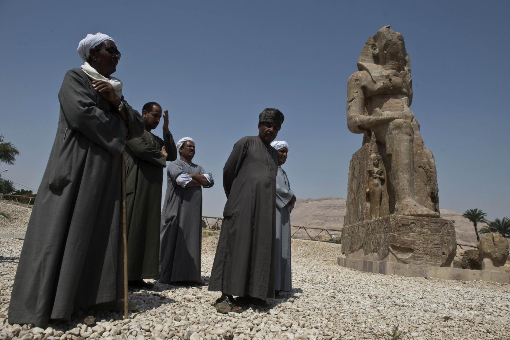 Archaeology staff in Luxor stand next to one of two newly displayed statues of the pharaoh Amenhotep III in the Egyptian city. Photo: AFP