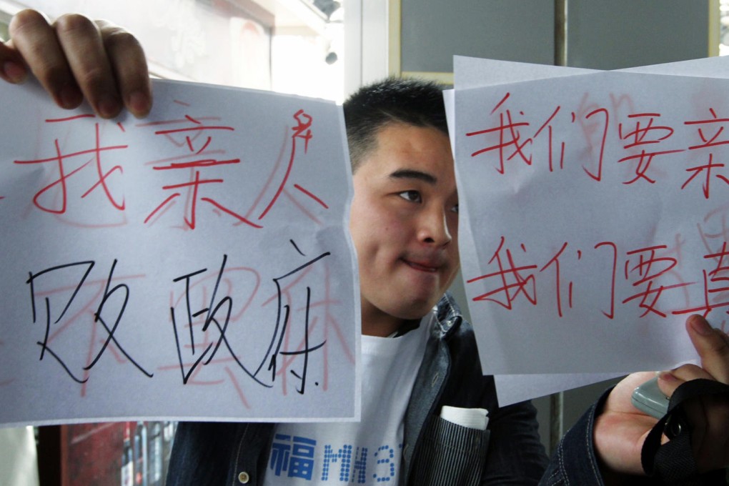 Relatives of passengers aboard flight MH370 hold signs sending good wishes to their loved ones and requesting the truth from the Malaysian government as they head for a protest at the country's embassy in Beijing. Photo: Simon Song
