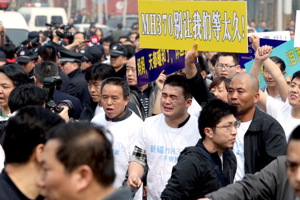 Family members of MH370 passengers hold up placards in a protest outside the Malaysian embassy in Beijing on March 25. Photo: SCMP/Simon Song