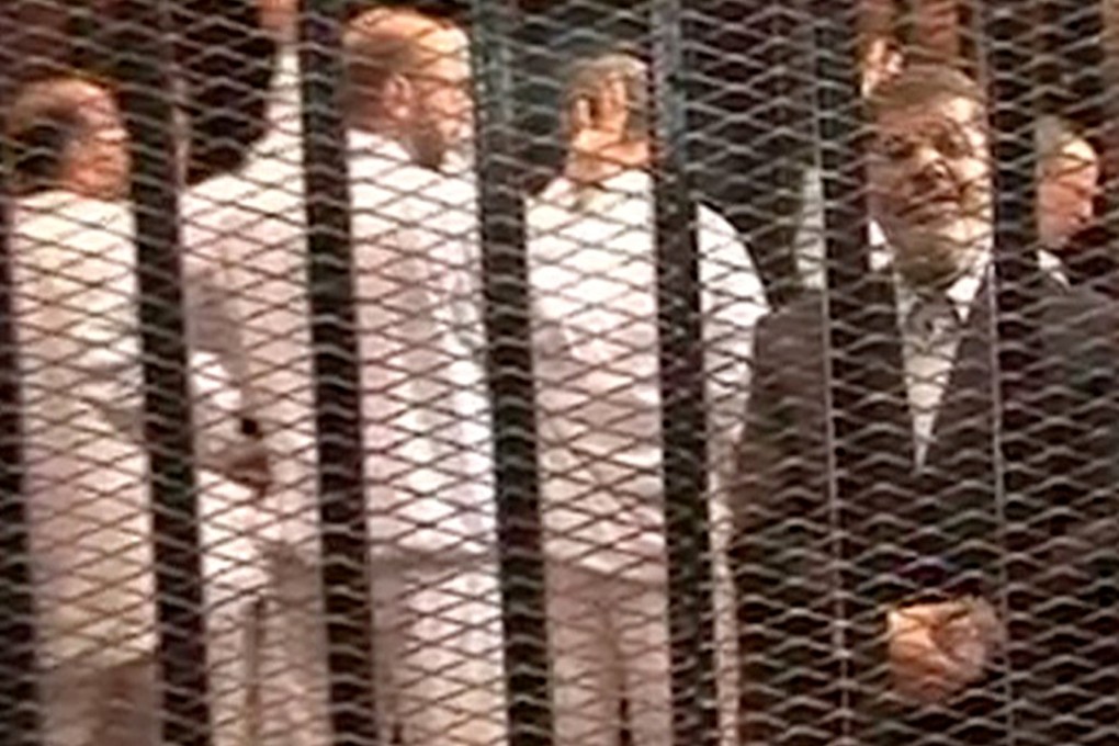 Mohammed Mursi (right) speaks from defendant's cage as he stands with co-defendants during a trial hearing in Cairo. Photo: AP