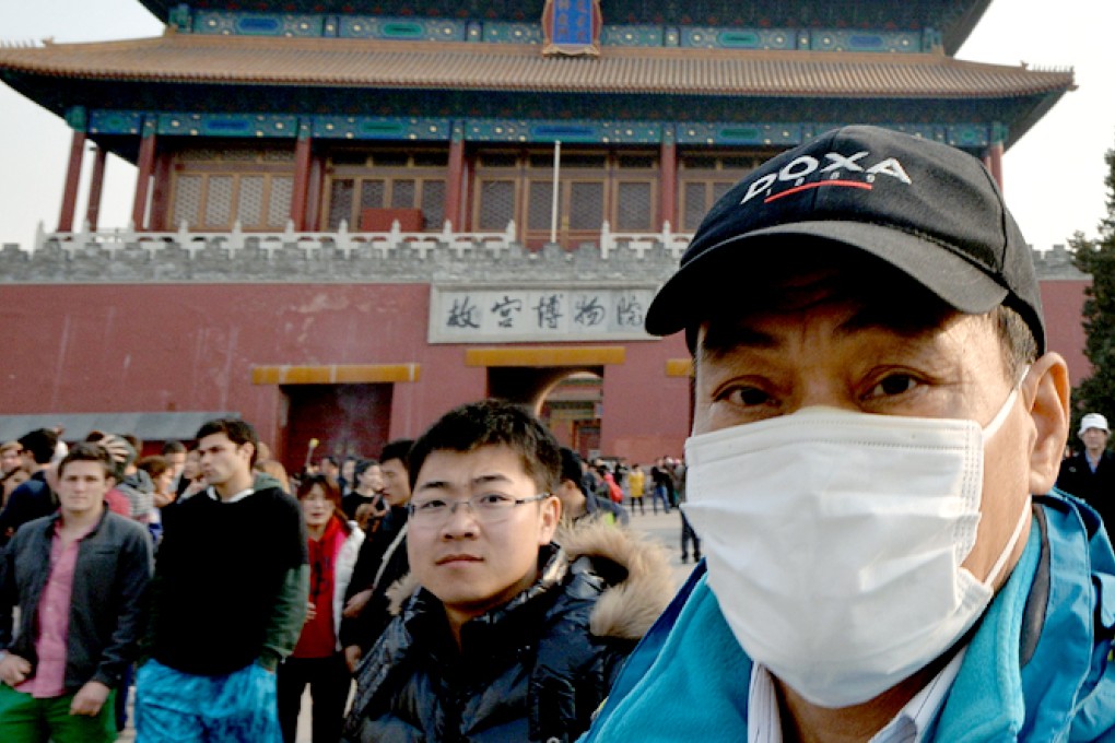 A Chinese tourist wears a facemask to protect himself against air pollution outside the Forbidden City in Beijing. Photo: AFP