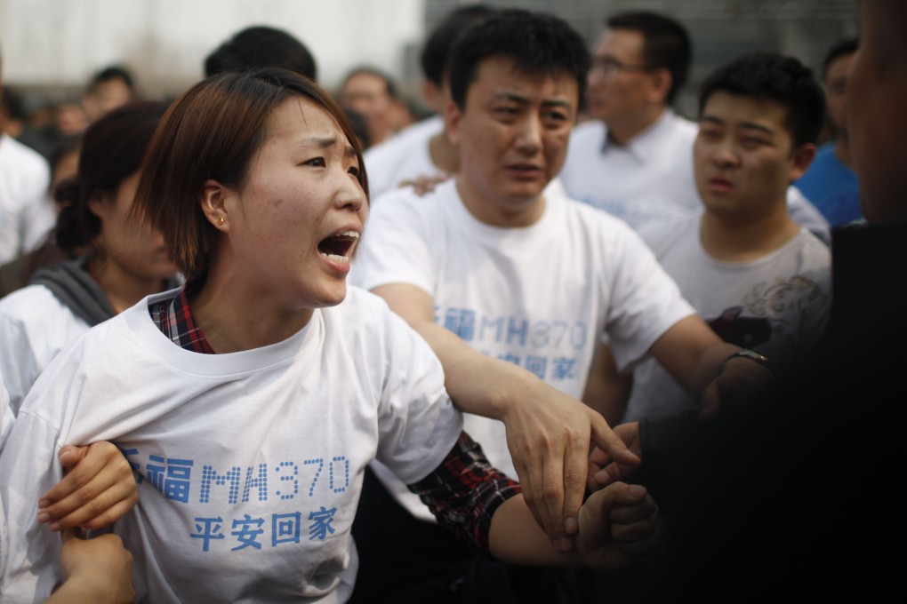 A relative of passengers on missing Malaysia Airlines flight MH370 yells at a security personnel during a protest outside the Malaysian embassy in Beijing on Tuesday.