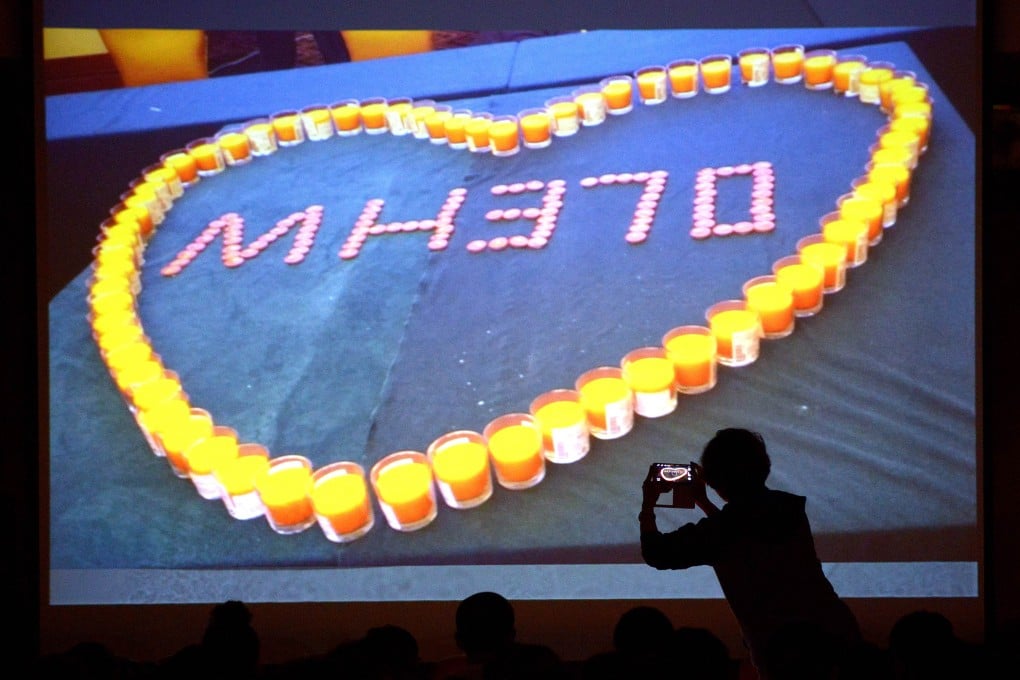 A woman takes a photo of a screen showing candlelights for relatives of passengers on the missing Malaysia Airlines flight MH370 before a meeting at the Metro Park Lido Hotel in Beijing. Photo: AFP