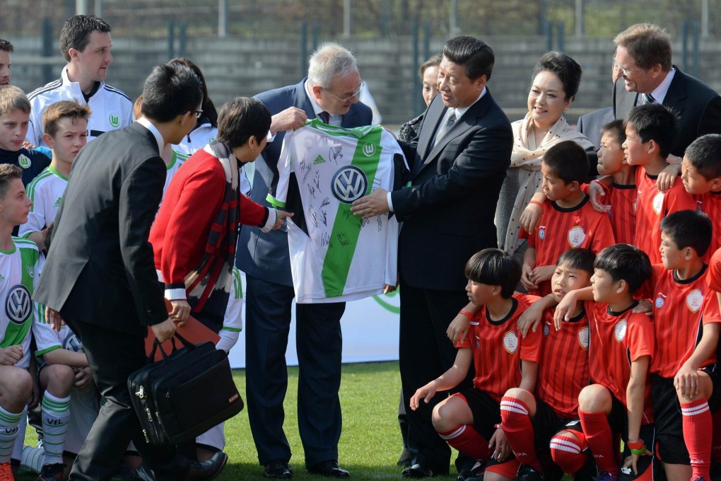 Volkswagen chief Martin Winterkorn presents a soccer shirt to Xi and wife Peng Liyuan at a match involving Chinese youngsters. Photo: AFP