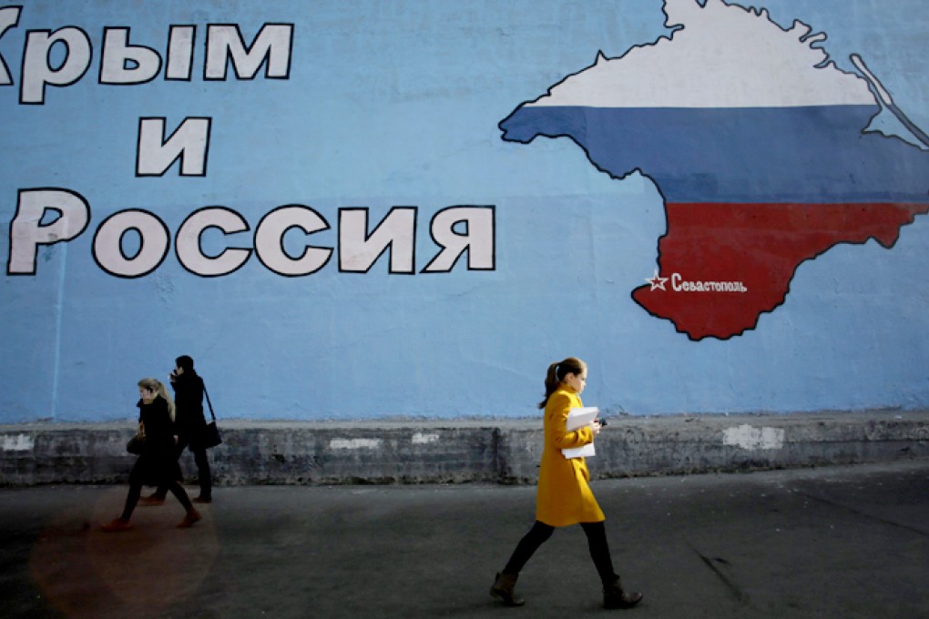 People walk past a mural showing a map of Crimea in the Russian national colours on a street in Moscow. Photo: Reuters