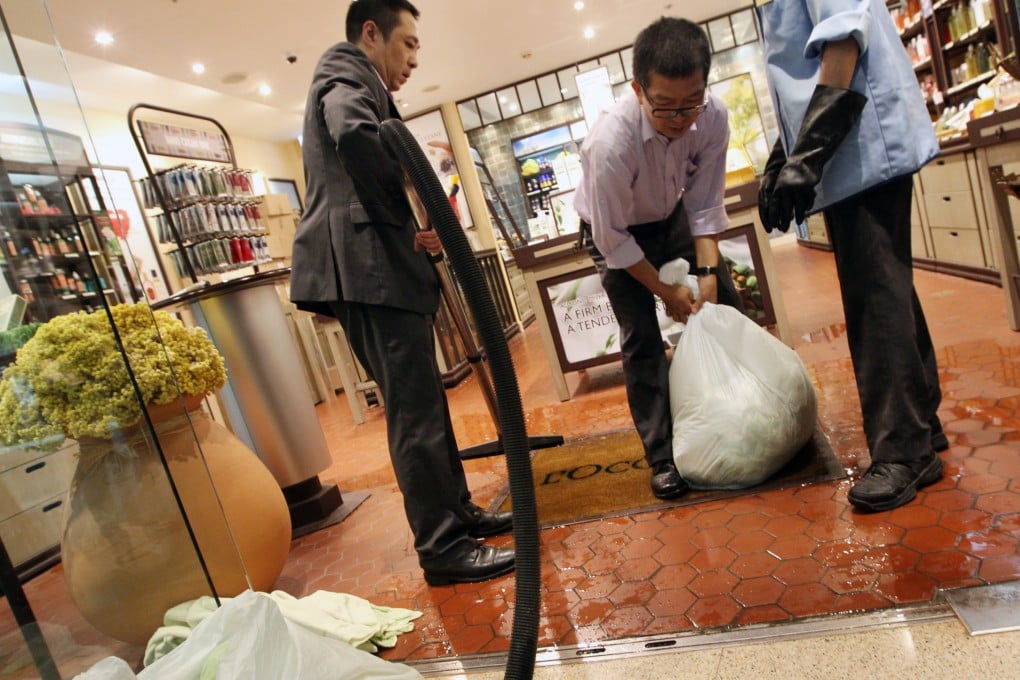 Staff are busy mopping the floor at Festival Walk after the mall was flooded under the black rainstorm warning signal. Photo: Felix Wong