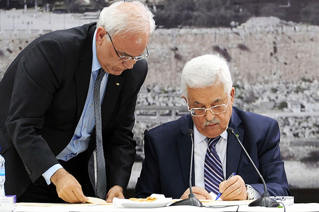 Palestinian President Mahmoud Abbas signs a request on joining 15 United Nations agencies and international treaties during a meeting with Palestinian leaders at his office in the West Bank city of Ramallah. Photo: Xinhua