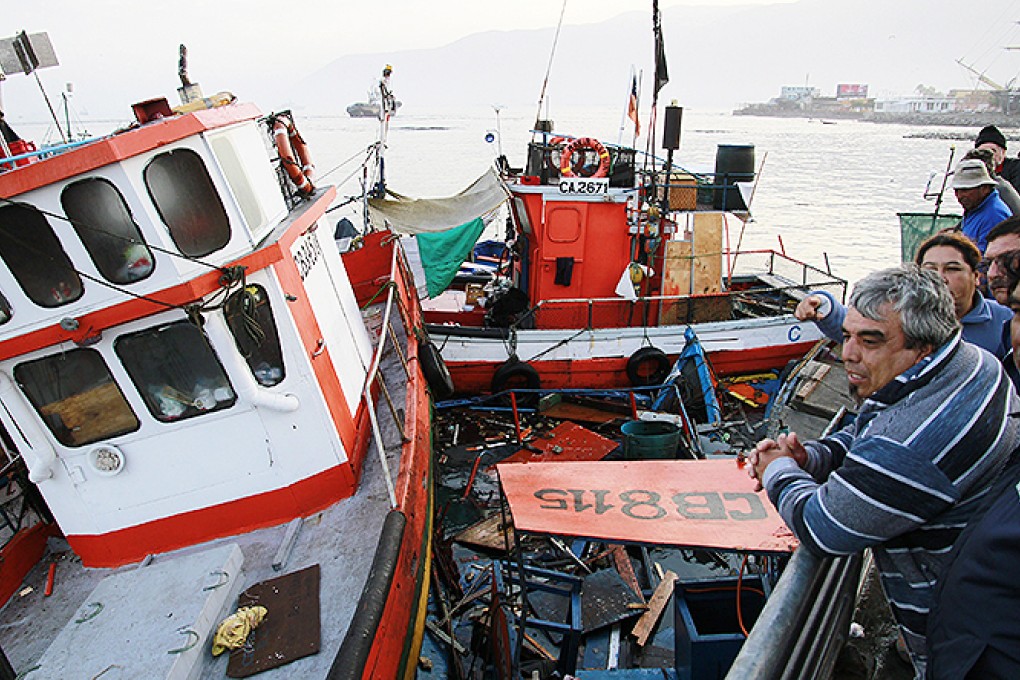 People look at boats washed up after the earthquake in the harbour at Iquique. Photo: AFP