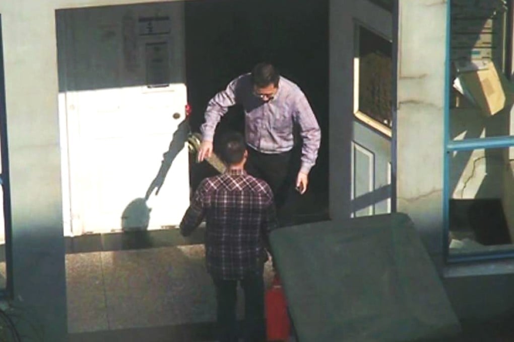 A man said to be Wu Weimin collects a parcel from a man outside his home. Photo: SCMP