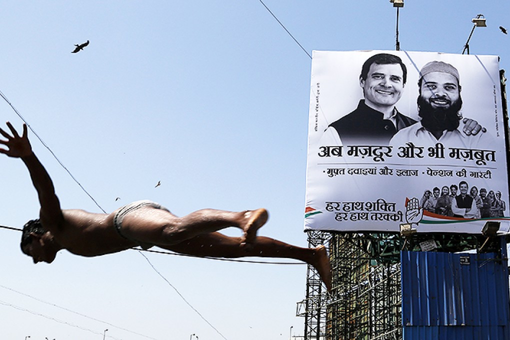 A boy dives into the Arabian Sea in Mumbai as a banner for India's ruling Congress party featuring vice president Rahul Gandhi is erected. Photo: AP