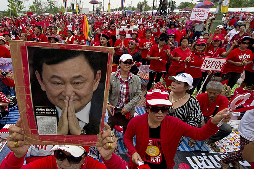 A Thai red shirt protester holds a portrait of fugitive former premier Thaksin Shinawatra. Photo: AFP