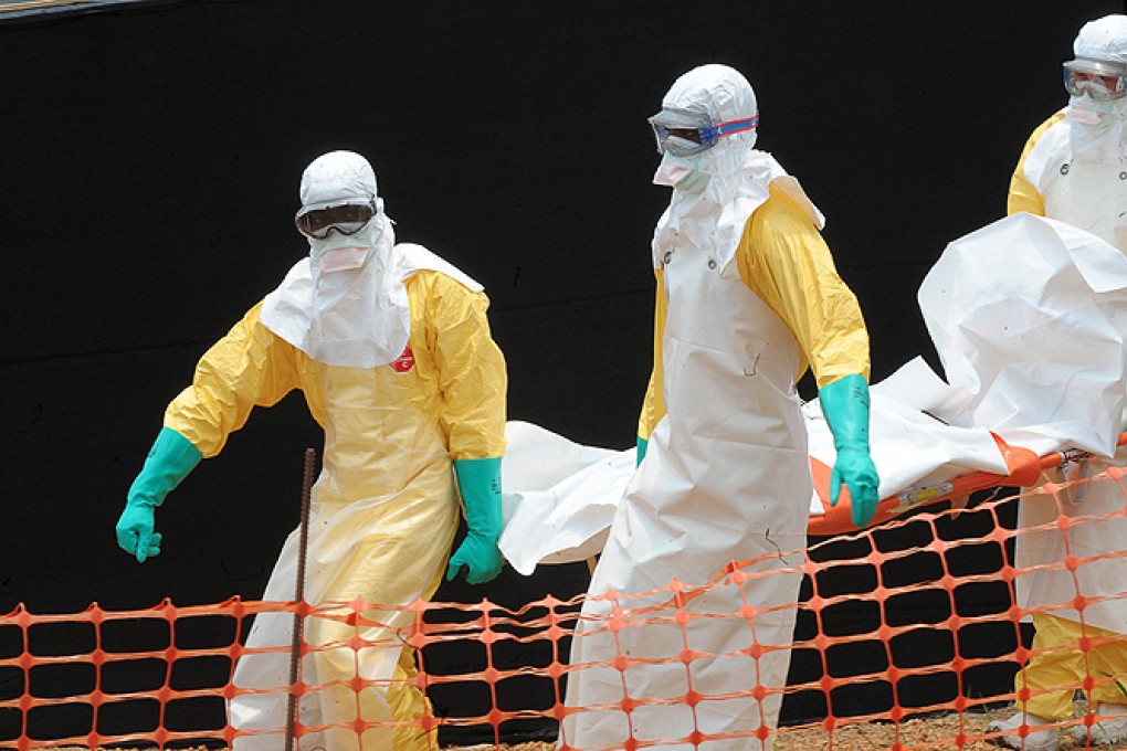 Medecin Sans Frontieres staff carry the body of a person killed by Ebola at a treatment centre in Guekedou, Guinea. Photo: AFP