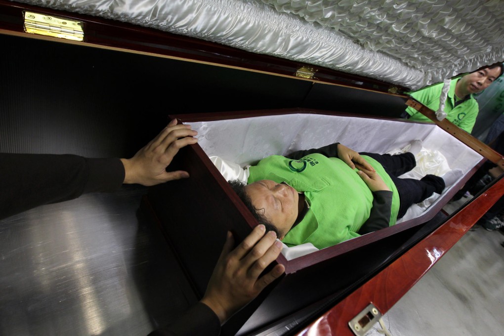 Green Life Passage chief executive Lam Ka-hei tries one of the reusable coffins for size at the group's San Po Kong offices. Photo: Dickson Lee