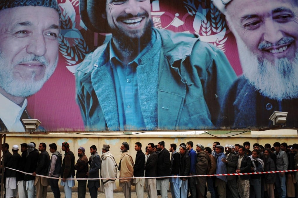 Men vote under a billboard showing Hamid Karzai and deceased Afghan figures Ahmad Shah Massoud and Burhandin Rabani. Photo: AFP