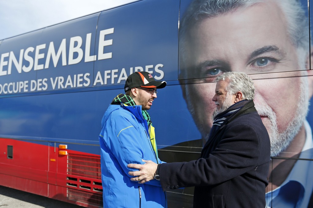 Liberal leader Philippe Couillard shakes the hand of a supporter in Roberval, Quebec on Monday. Photo: Reuters
