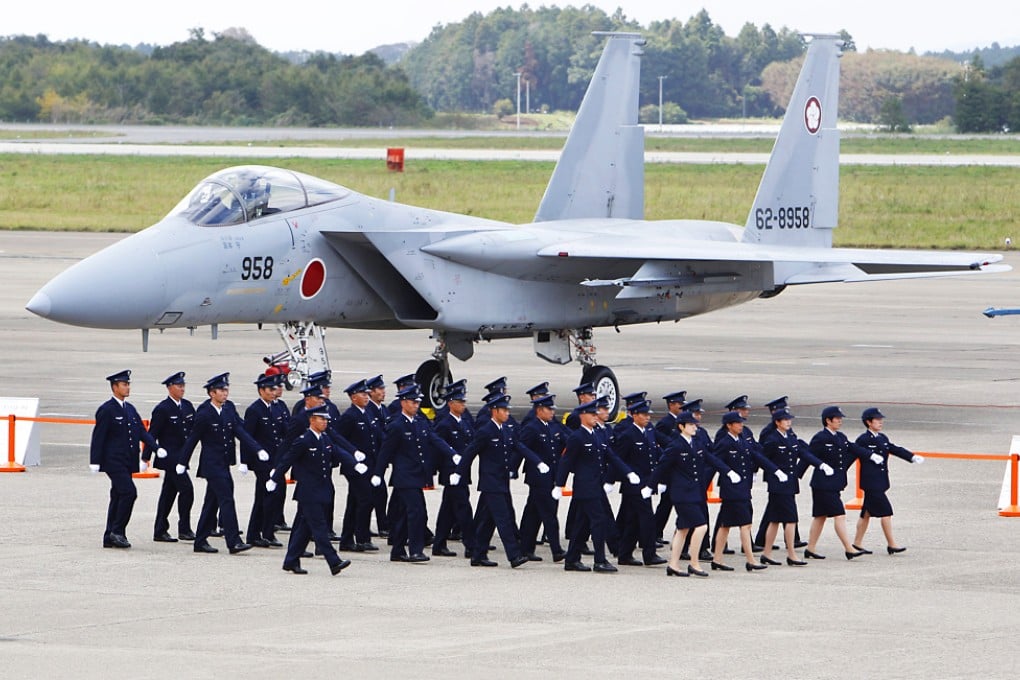 Japan Self-Defense Force members walk in front of F-15 J/DJ Fighter during the annual Self-Defense Forces Commencement of Air Review at Hyakuri Air Base, north of Tokyo in 2011. Photo: AP