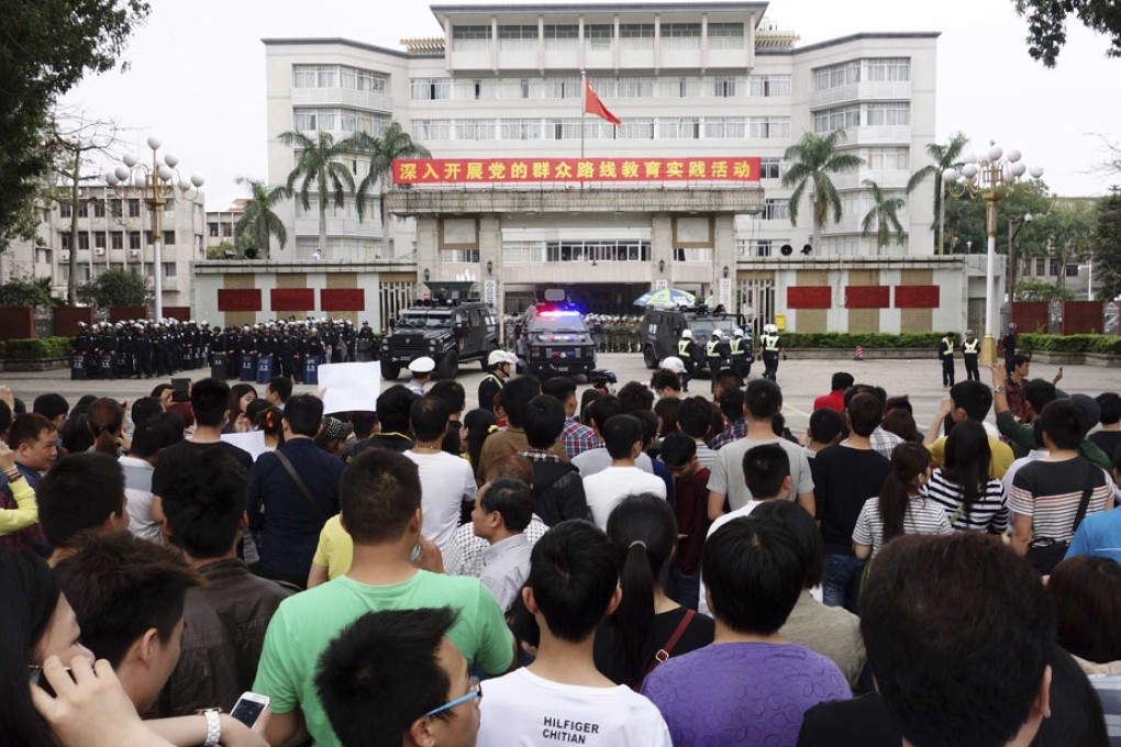Riot policemen guard the city government building as demonstrators gather to protest against a chemical plant project, in Maoming on April 3, 2014. Photo: Reuters
