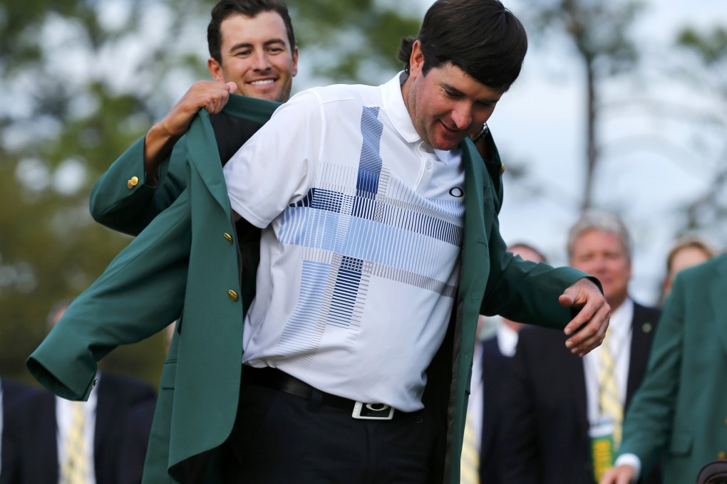 Masters champion Bubba Watson of the US  is helped with his traditional green jacket by last year's champion Adam Scott. Photo: Reuters