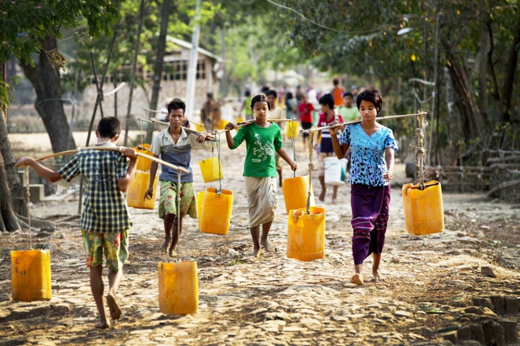 Residents of Dala, near Yangon, carry plastic containers filled with drinking water fetched from a natural pond. Photo: AP