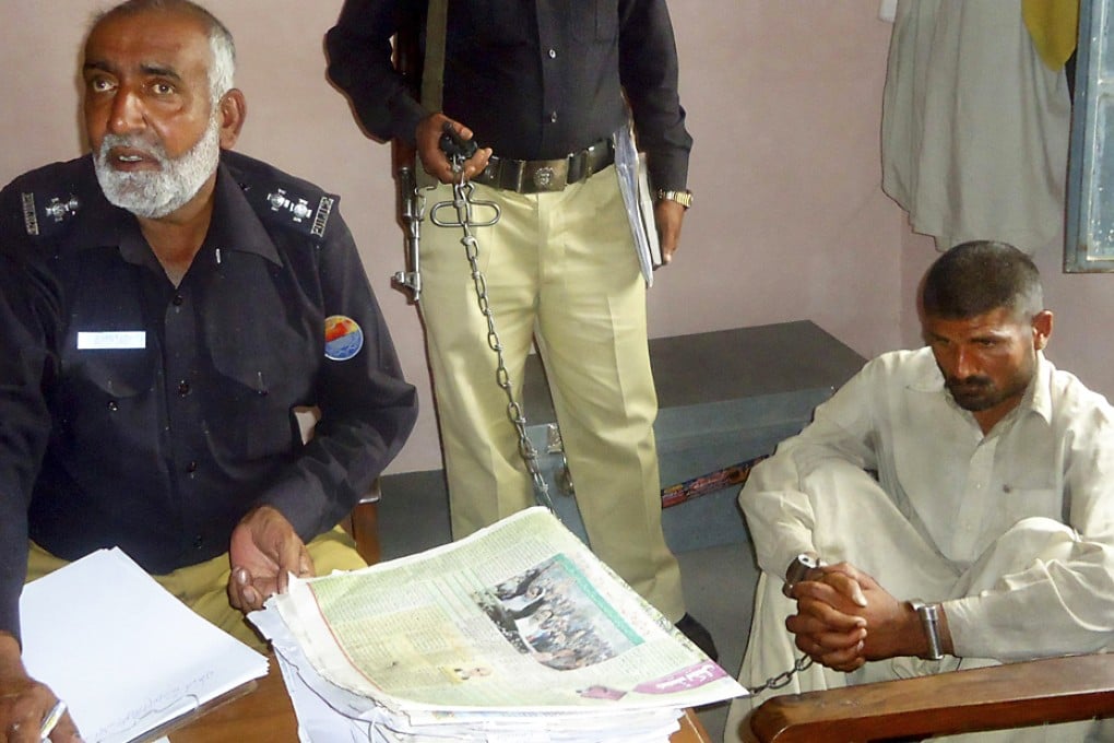 Mohammad Arif (right) sits in a police custody at a police station in Bhakkar, Punjab. Photo: Reuters