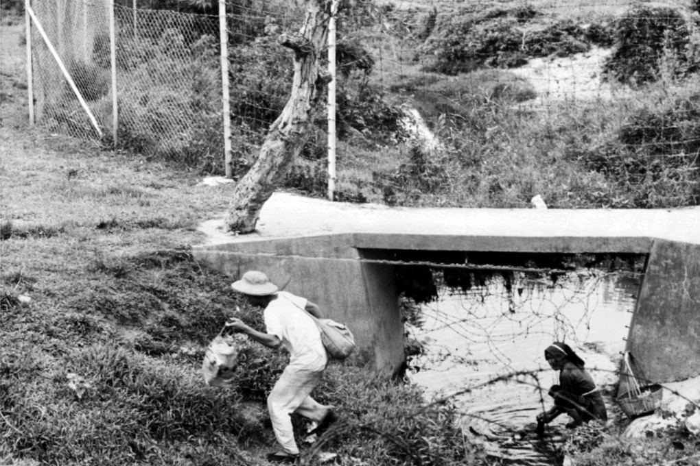 An illegal immigrant enters Hong Kong the hard way in 1962, wading through a stream under barbed wire. Photos: GIS; Bloomberg