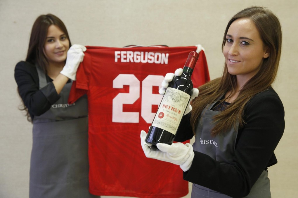 Christie's staff with the signed Manchester United Champions League shirt from 1999 and one of the bottles to go on sale. Photo: Reuters