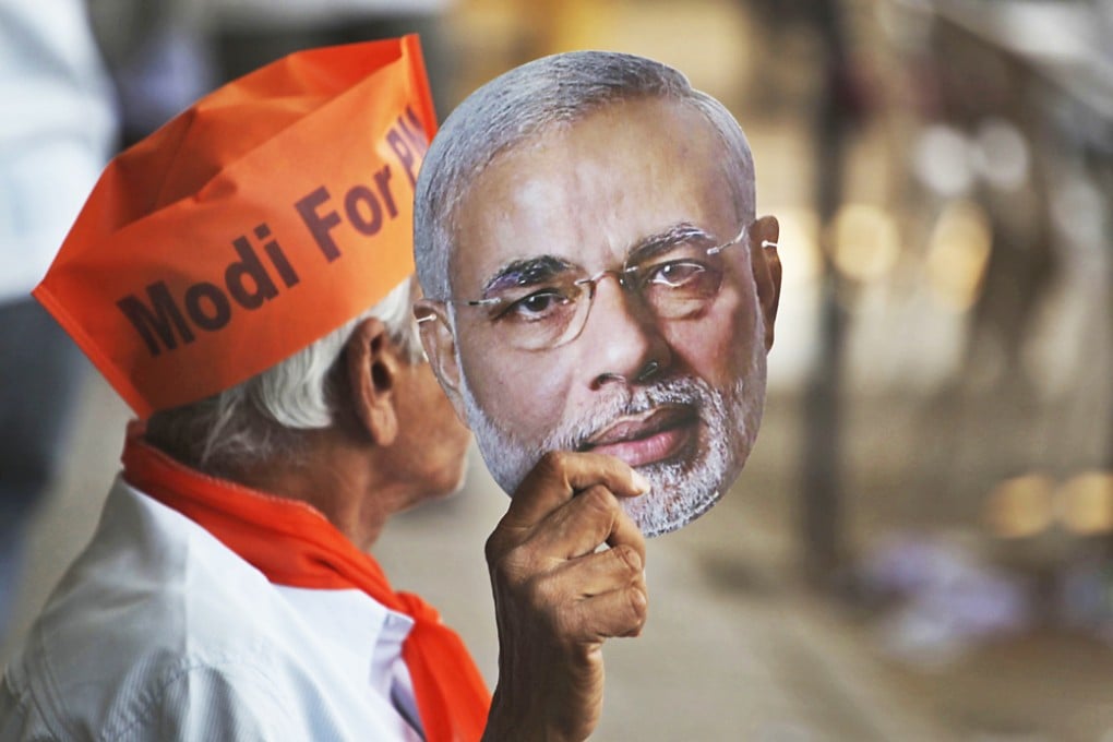 A Modi supporter holds a mask of prime ministerial candidate Narendra Modi at an election campaign road show rally in Ahmadabad. Photo: AP